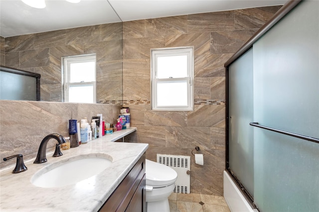 590 Langley Ave, West Hempstead, NY 11552 - full bath featuring radiator, vanity, tile walls, toilet, and combined bath / shower with glass door