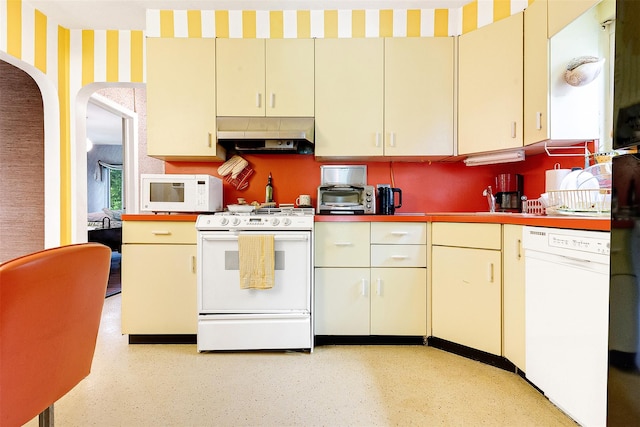 85-82 66th Rd, Rego Park, NY 11374 - kitchen with white appliances, under cabinet range hood, wallpapered walls, cream cabinetry, and arched walkways