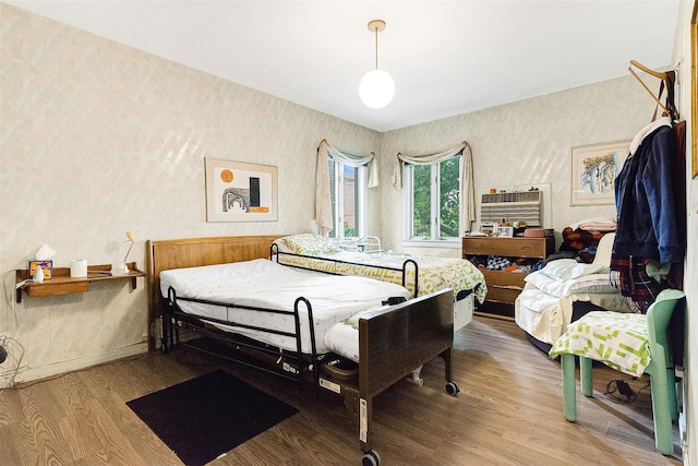 85-82 66th Rd, Rego Park, NY 11374 - bedroom featuring wood finished floors, wallpapered walls, an AC wall unit, and baseboards