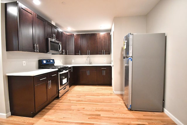 86 Lander St, Newburgh, NY 12550 - kitchen with appliances with stainless steel finishes, light wood-type flooring, light countertops, dark brown cabinetry, and baseboards