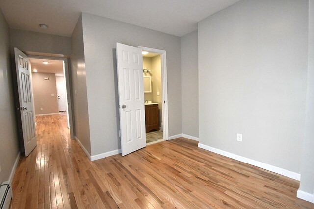 86 Lander St, Newburgh, NY 12550 - unfurnished bedroom with a baseboard radiator, light wood-style flooring, and baseboards