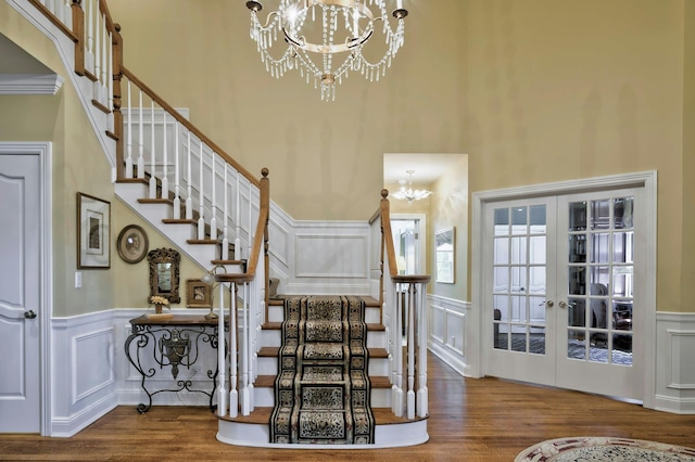 21 Hathaway Ln, Manhasset, NY 11030 - stairway featuring a chandelier, a decorative wall, wood finished floors, wainscoting, and a towering ceiling