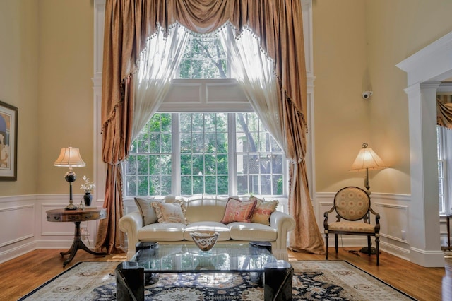 21 Hathaway Ln, Manhasset, NY 11030 - living room featuring a decorative wall, wainscoting, decorative columns, wood finished floors, and a towering ceiling