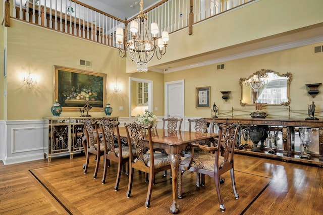 21 Hathaway Ln, Manhasset, NY 11030 - dining space featuring a chandelier, a high ceiling, wood finished floors, a wainscoted wall, and ornamental molding