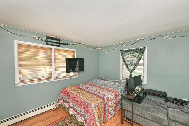 2 Anvil Ln, Levittown, NY 11756 - bedroom featuring a baseboard heating unit, multiple windows, and wood finished floors