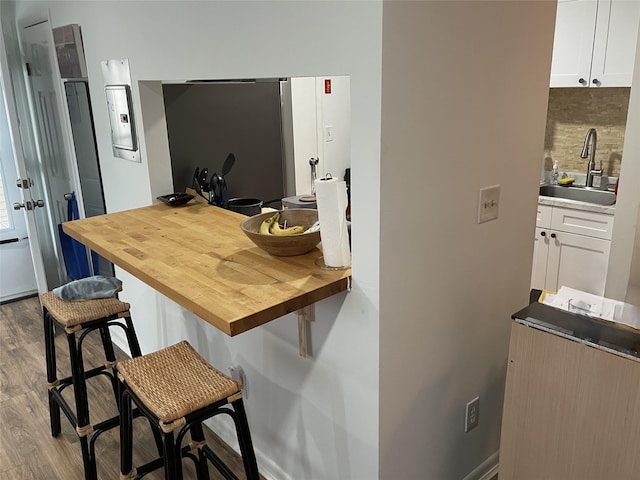 340 Concord Ln, Middletown, NY 10940 - kitchen with a sink, wood counters, a breakfast bar area, wood finished floors, and backsplash