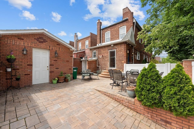 11401 115th St, South Ozone Park, NY 11420 - rear view of property featuring brick siding, a patio, outdoor dining area, and a chimney