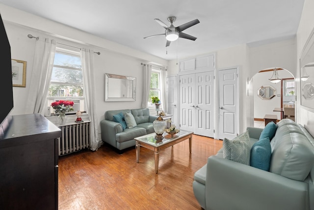 11401 115th St, South Ozone Park, NY 11420 - living room with radiator heating unit, ceiling fan, arched walkways, and light wood-style flooring