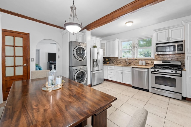 11401 115th St, South Ozone Park, NY 11420 - kitchen with stainless steel appliances, stacked washing machine and dryer, tasteful backsplash, light tile patterned floors, and arched walkways