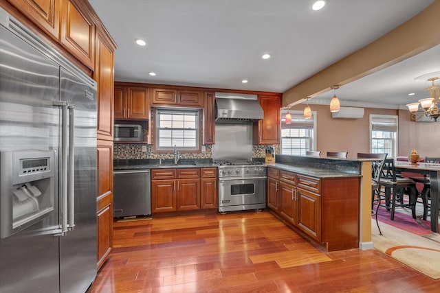 90 Milford St, Brooklyn, NY 11208 - kitchen featuring premium appliances, wall chimney exhaust hood, brown cabinets, a peninsula, and recessed lighting