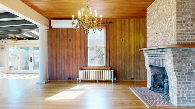150 Senix Ave, Center Moriches, NY 11934 - living room with radiator heating unit, a chandelier, hardwood / wood-style flooring, wood walls, and a brick fireplace