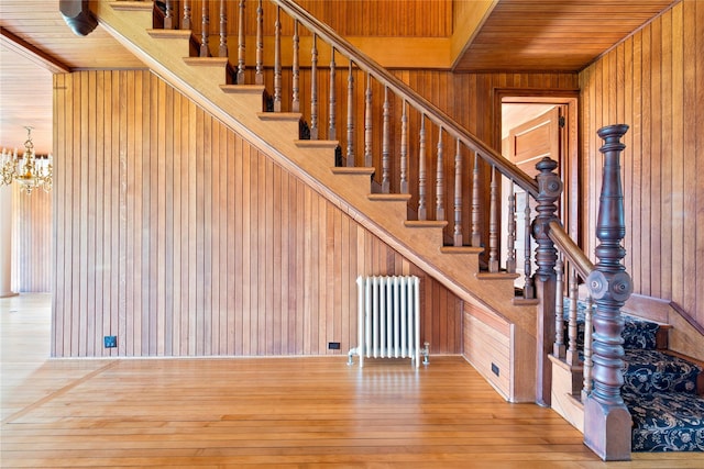 150 Senix Ave, Center Moriches, NY 11934 - stairs featuring radiator heating unit, wood walls, wooden ceiling, wood-type flooring, and a chandelier