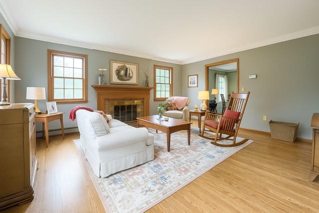 73 Gregory Way, Calverton, NY 11933 - living area with light wood-style floors, baseboard heating, crown molding, and a fireplace