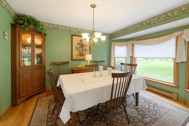 73 Gregory Way, Calverton, NY 11933 - dining room with baseboard heating, a chandelier, light wood-style flooring, and baseboards