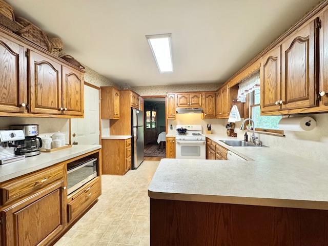 73 Gregory Way, Calverton, NY 11933 - kitchen with appliances with stainless steel finishes, a sink, light countertops, brown cabinetry, and a peninsula