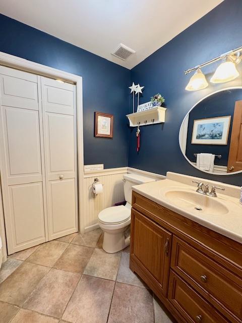 73 Gregory Way, Calverton, NY 11933 - bathroom featuring vanity, toilet, wainscoting, and tile patterned flooring