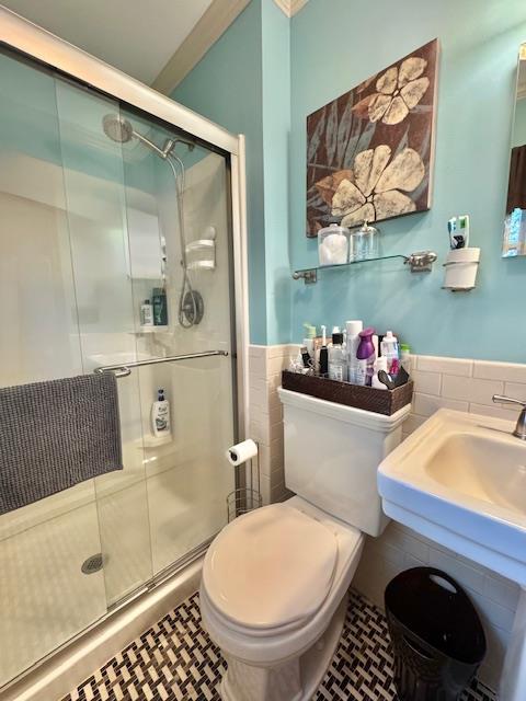 73 Gregory Way, Calverton, NY 11933 - bathroom with tile walls, toilet, a shower stall, a wainscoted wall, and tile patterned floors