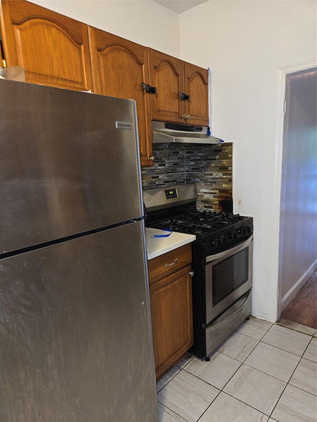 731 E 218th St, Bronx, NY 10467 - kitchen featuring appliances with stainless steel finishes, under cabinet range hood, tasteful backsplash, light tile patterned floors, and light countertops