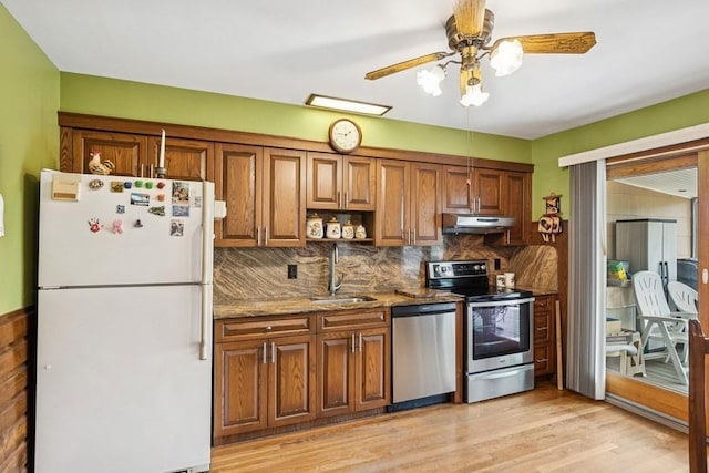473 S 15th St, Lindenhurst, NY 11757 - kitchen with stainless steel appliances, under cabinet range hood, brown cabinets, light stone counters, and light wood-style floors