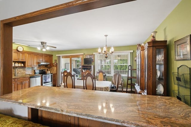 473 S 15th St, Lindenhurst, NY 11757 - kitchen with appliances with stainless steel finishes, under cabinet range hood, a chandelier, brown cabinets, and decorative backsplash