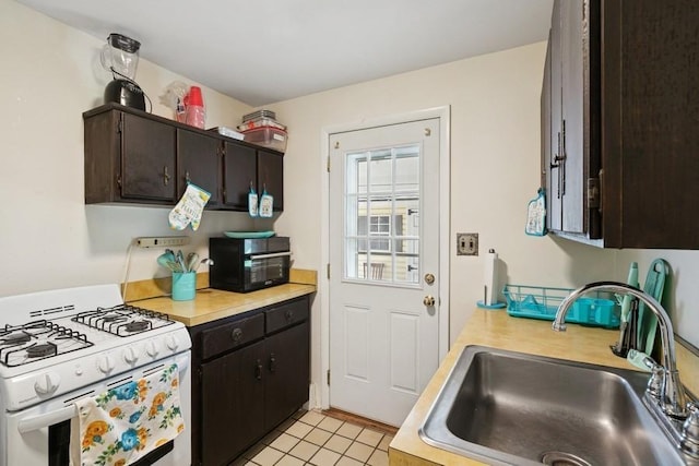 473 S 15th St, Lindenhurst, NY 11757 - kitchen with white gas stove, light countertops, light tile patterned floors, and dark brown cabinets
