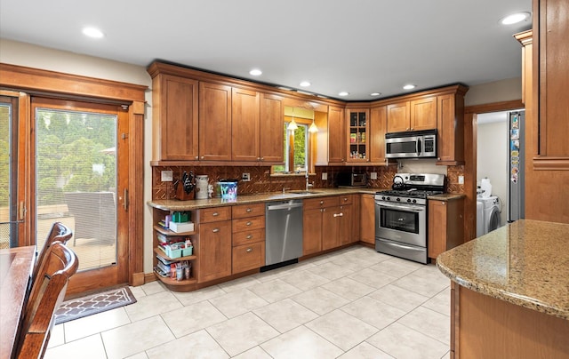 11 Gilford Ct, Melville, NY 11747 - kitchen featuring appliances with stainless steel finishes, a sink, brown cabinetry, decorative backsplash, and light stone counters