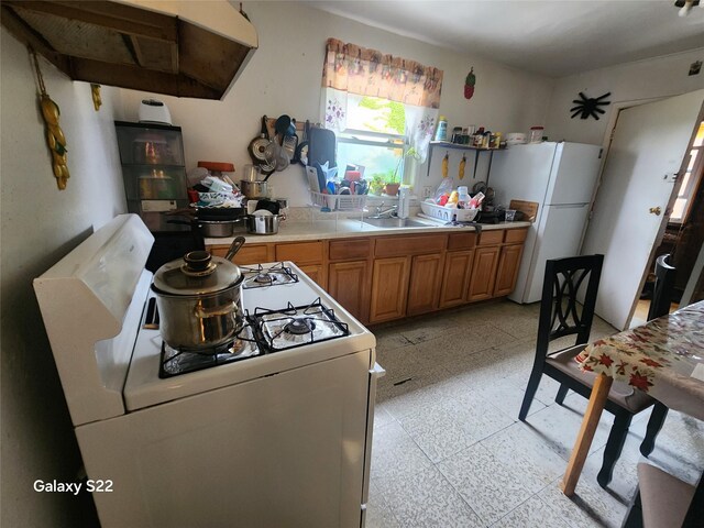 32 Yonkers Ave, Yonkers, NY 10701 - kitchen with white appliances, exhaust hood, light countertops, brown cabinets, and a sink