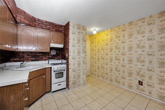 69-14 61st Rd, Middle Village, NY 11379 - kitchen with white gas range, under cabinet range hood, wallpapered walls, a sink, and light countertops