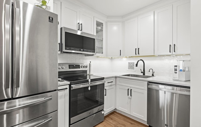 1101 162nd St Unit 6C, Beechhurst, NY 11357 - kitchen featuring stainless steel appliances, a sink, white cabinets, light countertops, and tasteful backsplash