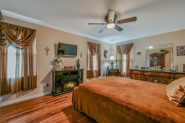 16 Abbey Ln, East Setauket, NY 11733 - bedroom with wood-type flooring, ornamental molding, multiple windows, baseboards, and a glass covered fireplace