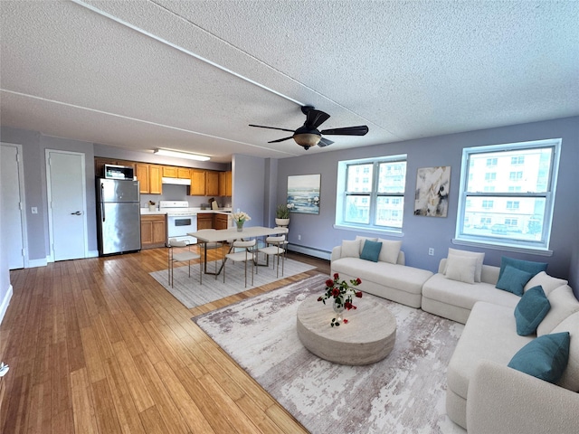 221 Bch 80th St Unit 2J, Rockaway Beach, NY 11693 - living room with a textured ceiling, wood finished floors, baseboard heating, ceiling fan, and baseboards