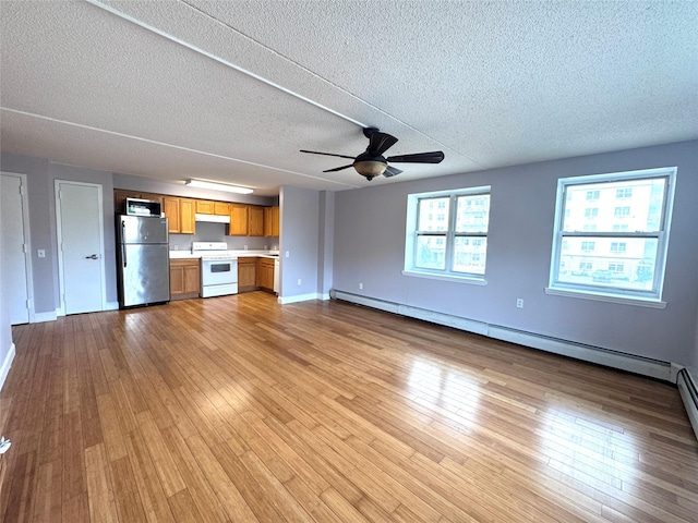 221 Bch 80th St Unit 2J, Rockaway Beach, NY 11693 - unfurnished living room with a baseboard heating unit, a textured ceiling, light wood-style floors, ceiling fan, and baseboards