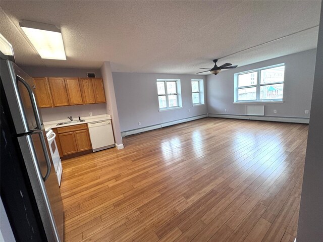 221 Bch 80th St Unit 2J, Rockaway Beach, NY 11693 - kitchen featuring freestanding refrigerator, white dishwasher, a baseboard heating unit, a sink, and a textured ceiling