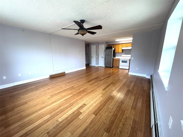 221 Bch 80th St Unit 2J, Rockaway Beach, NY 11693 - unfurnished living room with wood finished floors, a ceiling fan, baseboards, a textured ceiling, and a baseboard heating unit