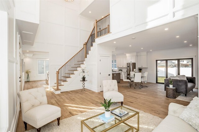 45 Mist Ln, Westbury, NY 11590 - living area featuring a towering ceiling, stairs, healthy amount of natural light, light wood finished floors, and recessed lighting
