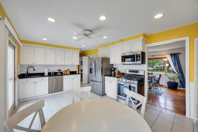 86 Woodbine Dr N, Hicksville, NY 11801 - kitchen with stainless steel appliances, light tile patterned floors, dark countertops, a ceiling fan, and white cabinetry