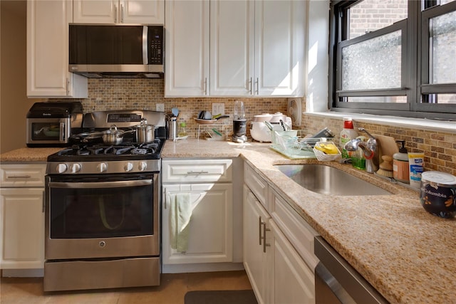 50 Brompton Unit 3K, Great Neck, NY 11021 - kitchen with stainless steel appliances, a sink, backsplash, white cabinets, and light stone countertops