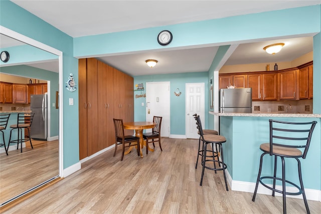 210 E Broadway Unit 1D, Long Beach, NY 11561 - kitchen featuring freestanding refrigerator, brown cabinets, a kitchen breakfast bar, and light wood-style floors