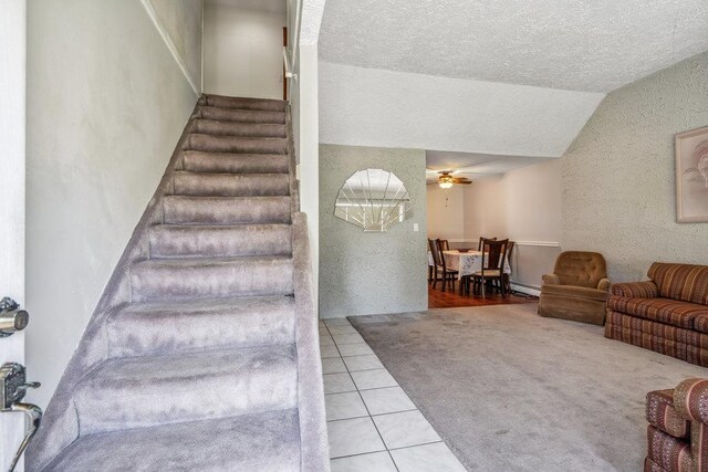 315 Fern Pl, Bethpage, NY 11714 - staircase featuring a ceiling fan, tile patterned floors, a textured ceiling, vaulted ceiling, and baseboard heating