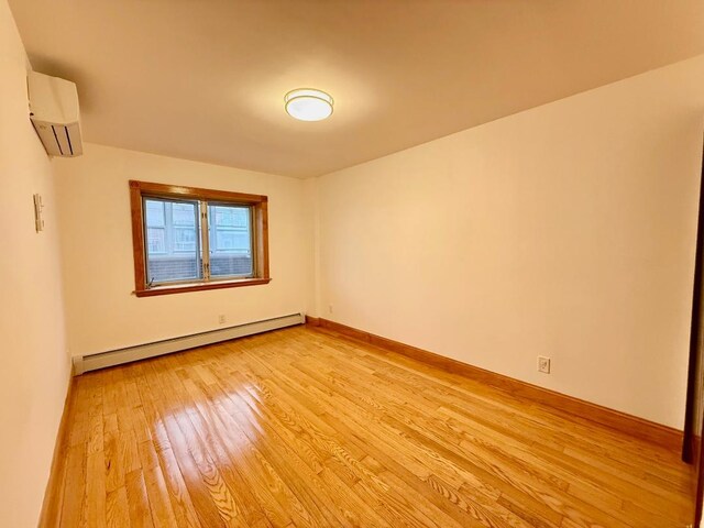 41-42 College Point Blvd Unit 3E, Flushing, NY 11355 - empty room featuring baseboard heating, a wall unit AC, light wood-type flooring, and baseboards