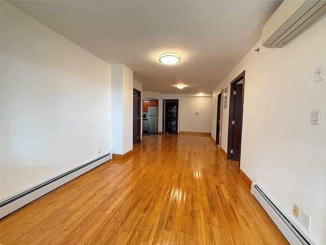 41-42 College Point Blvd Unit 3E, Flushing, NY 11355 - empty room with a baseboard radiator, a wall mounted air conditioner, light wood-style flooring, and baseboards