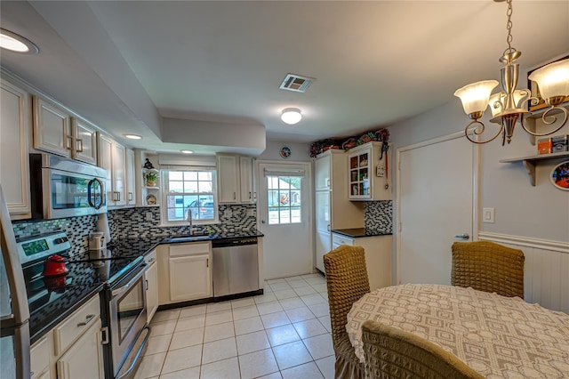 119 Exmore Ct Unit A, Ridge, NY 11961 - kitchen featuring appliances with stainless steel finishes, a sink, dark countertops, a chandelier, and backsplash