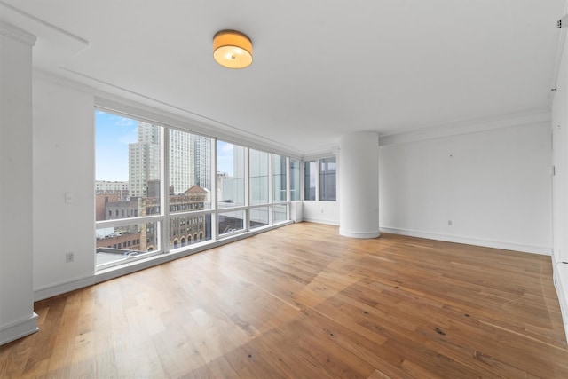5 Renaissance Sq Unit 10G, White Plains, NY 10601 - spare room with wood finished floors, ornamental molding, a view of city, baseboards, and a wall of windows