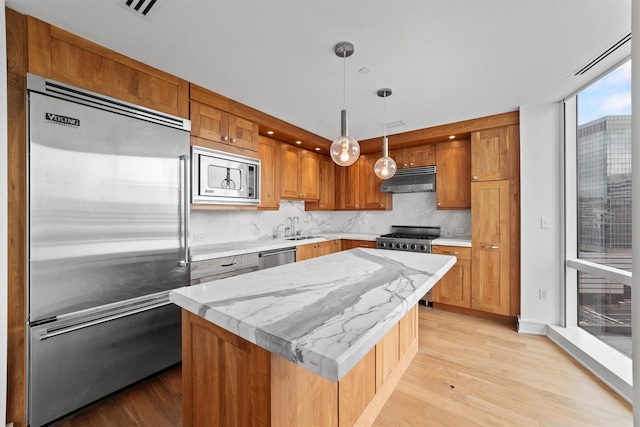 5 Renaissance Sq Unit 10G, White Plains, NY 10601 - kitchen featuring built in appliances, range hood, a sink, light wood-style floors, and tasteful backsplash