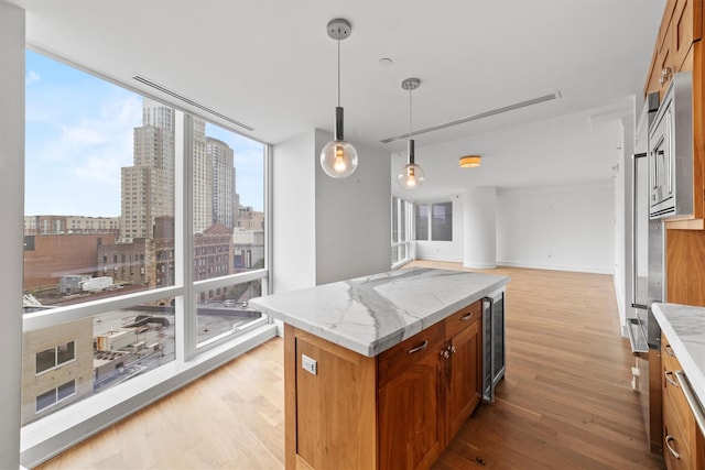 5 Renaissance Sq Unit 10G, White Plains, NY 10601 - kitchen with beverage cooler, light wood-style flooring, floor to ceiling windows, brown cabinets, and healthy amount of natural light