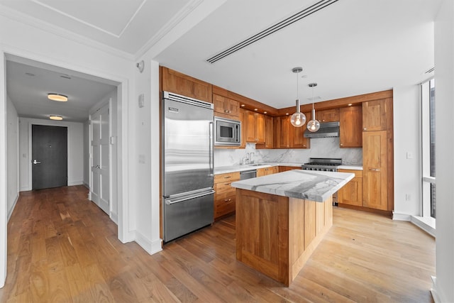 5 Renaissance Sq Unit 10G, White Plains, NY 10601 - kitchen with appliances with stainless steel finishes, under cabinet range hood, light wood finished floors, decorative backsplash, and light countertops