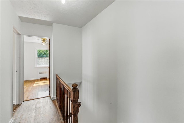 47-03 212th St, Bayside, NY 11361 - hallway with an upstairs landing, radiator heating unit, light wood-style floors, and a textured ceiling