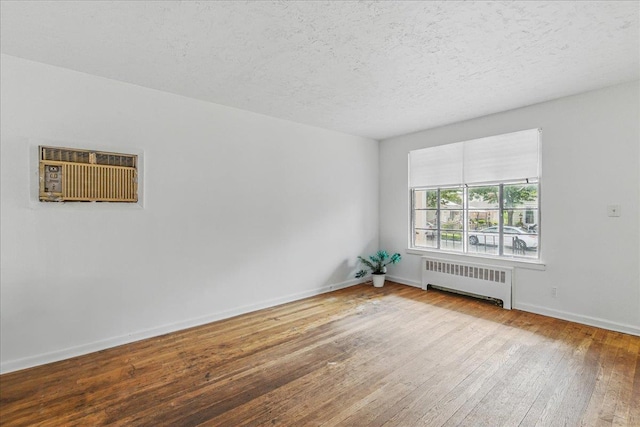 47-03 212th St, Bayside, NY 11361 - spare room featuring radiator heating unit, hardwood / wood-style floors, a wall mounted air conditioner, and a textured ceiling