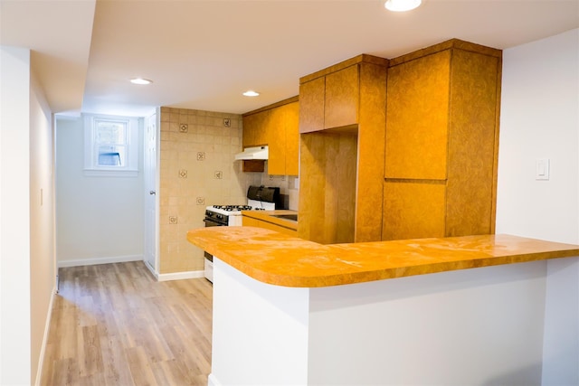 5428 65th Pl, Maspeth, NY 11378 - kitchen with white range with gas cooktop, light wood-style flooring, brown cabinets, under cabinet range hood, and baseboards