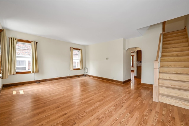 5428 65th Pl, Maspeth, NY 11378 - unfurnished living room with arched walkways, light wood-type flooring, stairway, and plenty of natural light